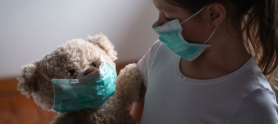 A child and teddy bear, both wearing medical masks