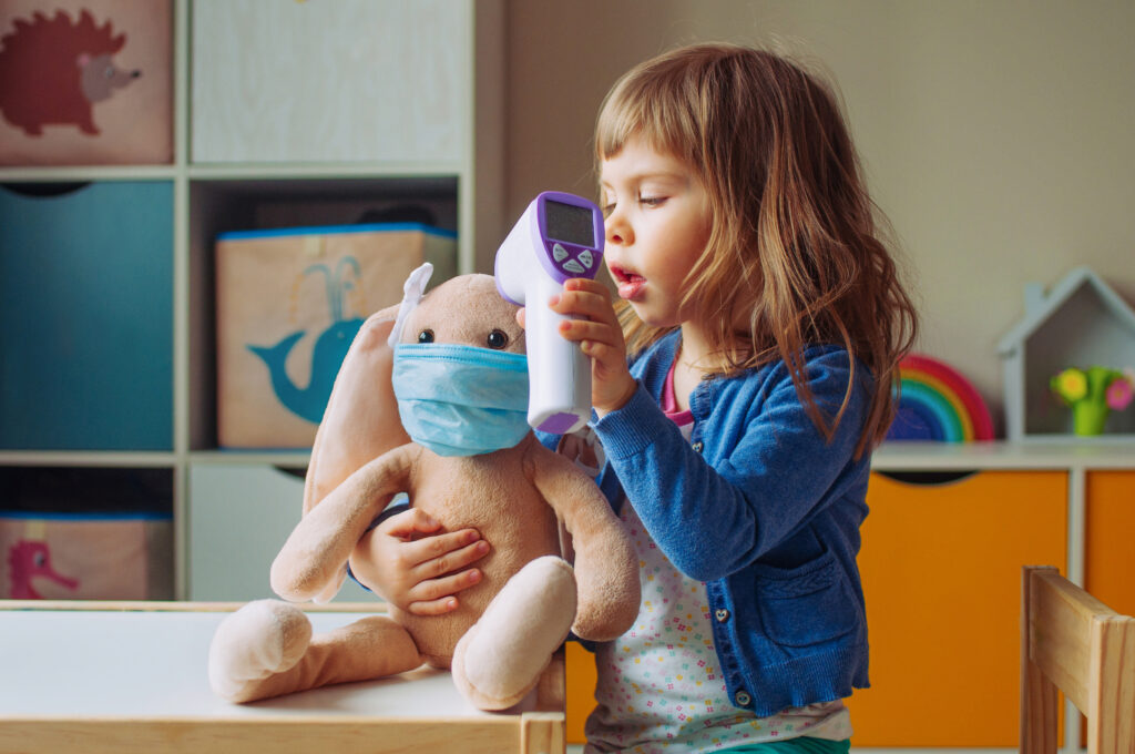 A child plays with a stuffed toy in a medical mask