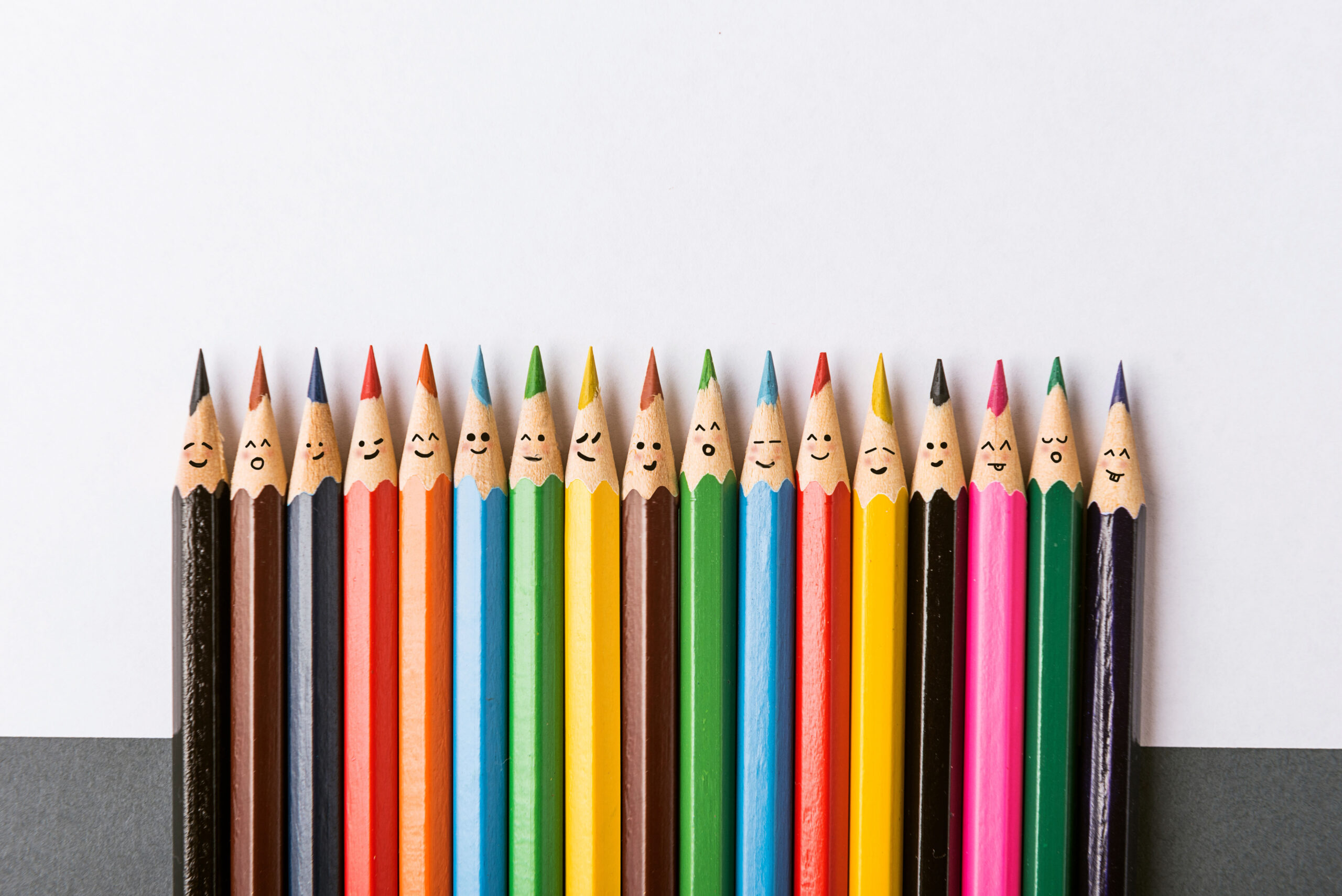 Une rangée de crayons de couleur différente avec des visages souriants