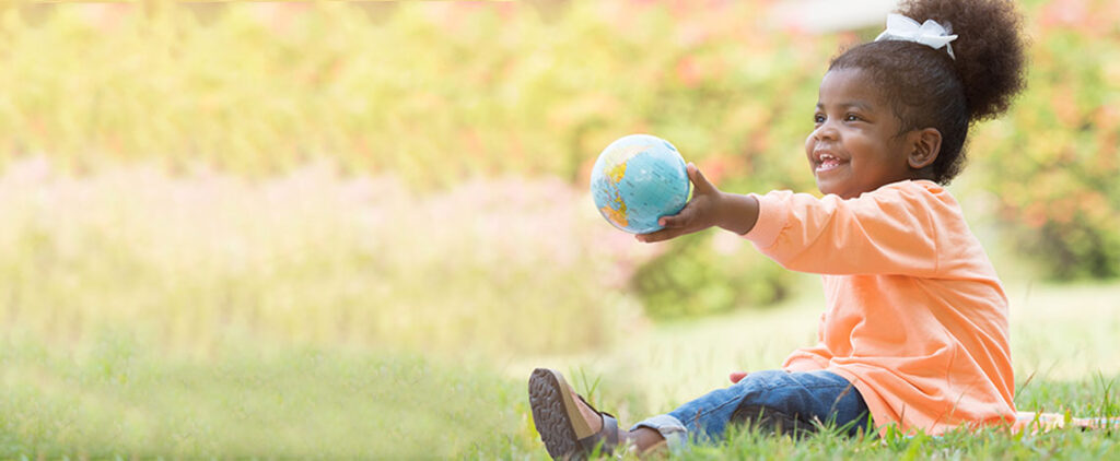 A small child holds a globe