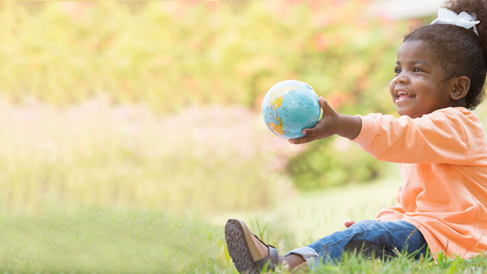 A small child holds a globe