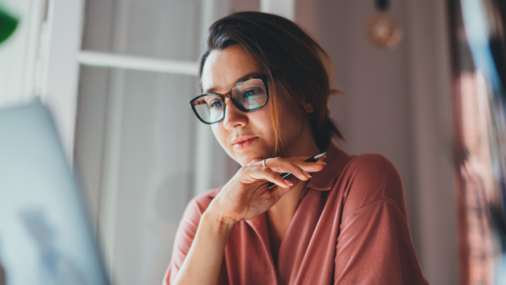 Femme qui regarde un écran d’ordinateur et réfléchit.